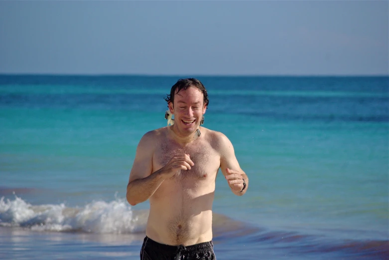 a man standing on a beach with his hands in his pockets