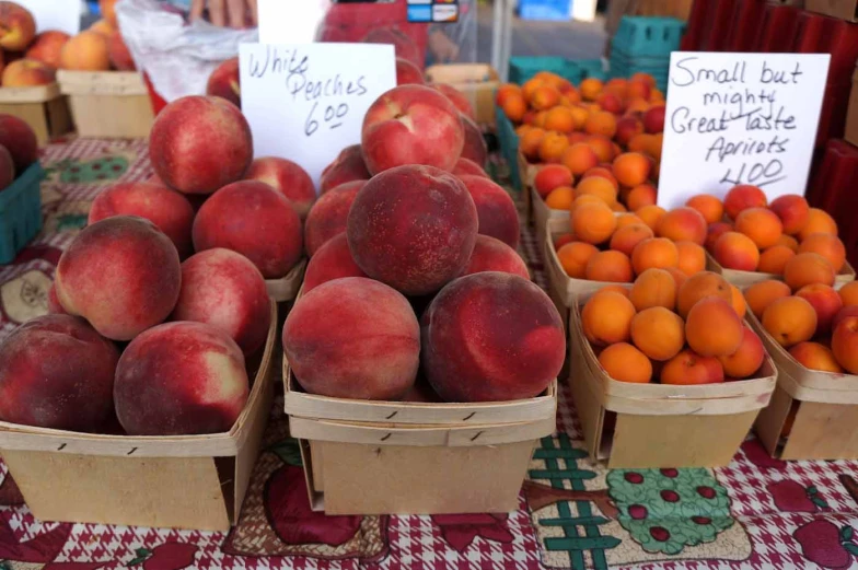 several baskets full of different fruits including peaches and oranges