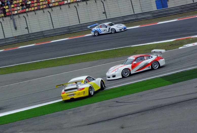 two race cars racing around the track, one has red and white stripes on it