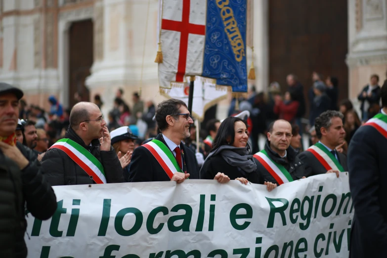 several people with flags and a banner at a street rally