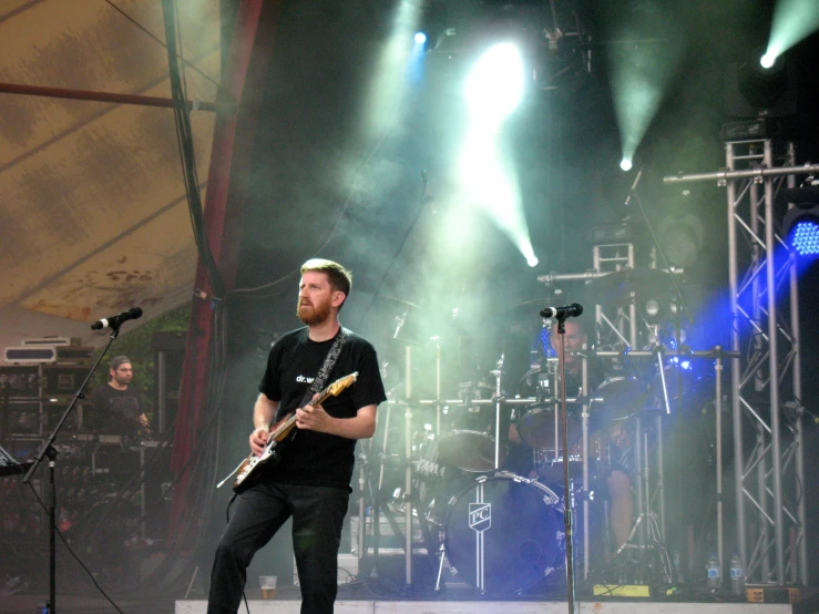 man playing guitar in front of lights during concert