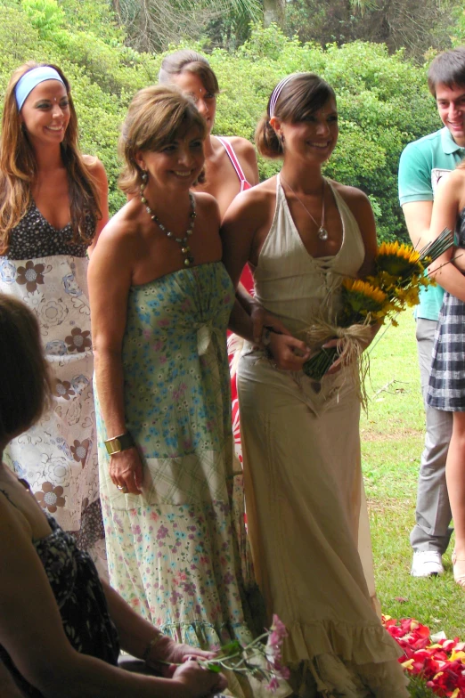 three women smile at the camera while another lady stands by holding flowers and smiles