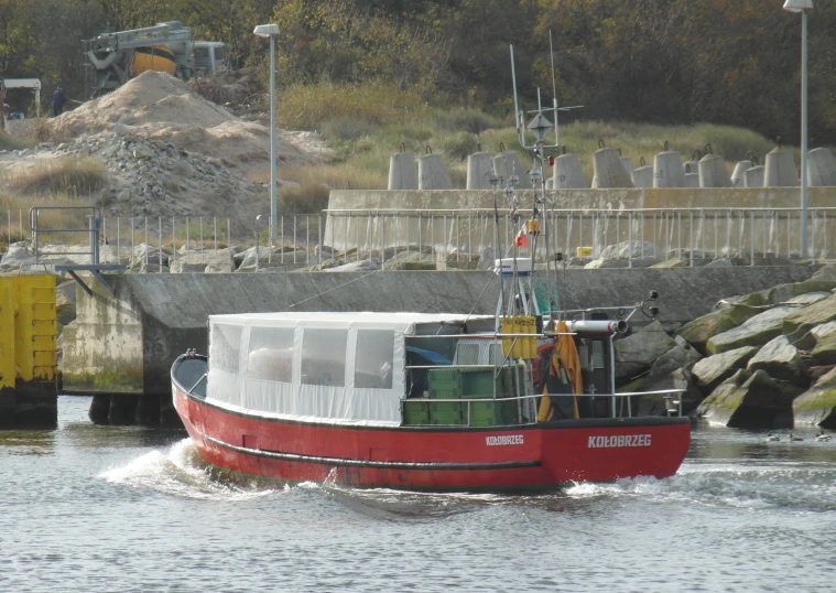 a red boat moving through the water near an overpass