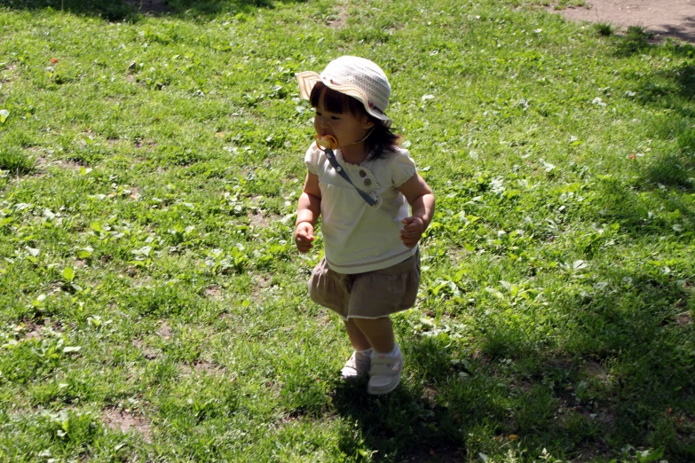 a little girl is walking in the grass