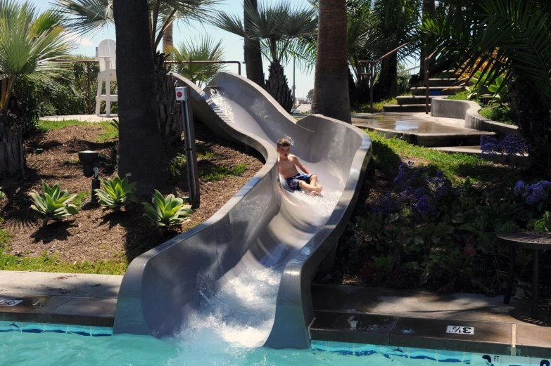 the little boy is sliding down the water slide