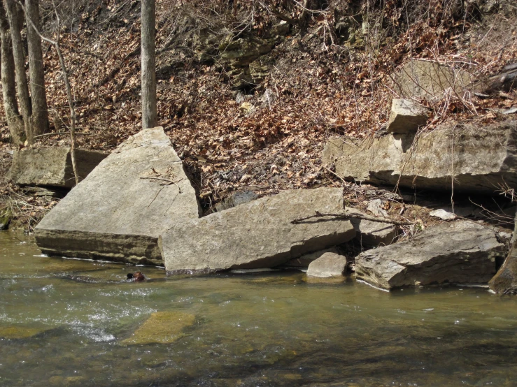 a person swimming between large rocks in the river