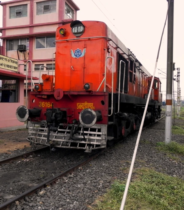 a large red train traveling past a building