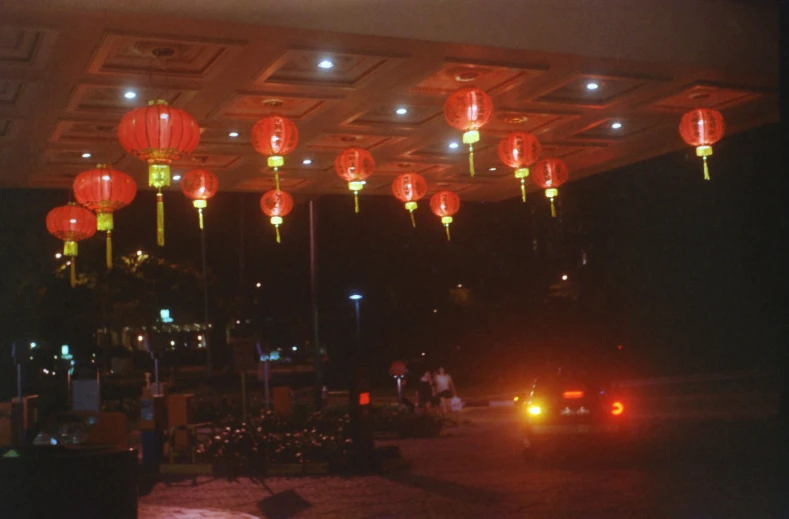 a car drives down a street lined with red paper lanterns