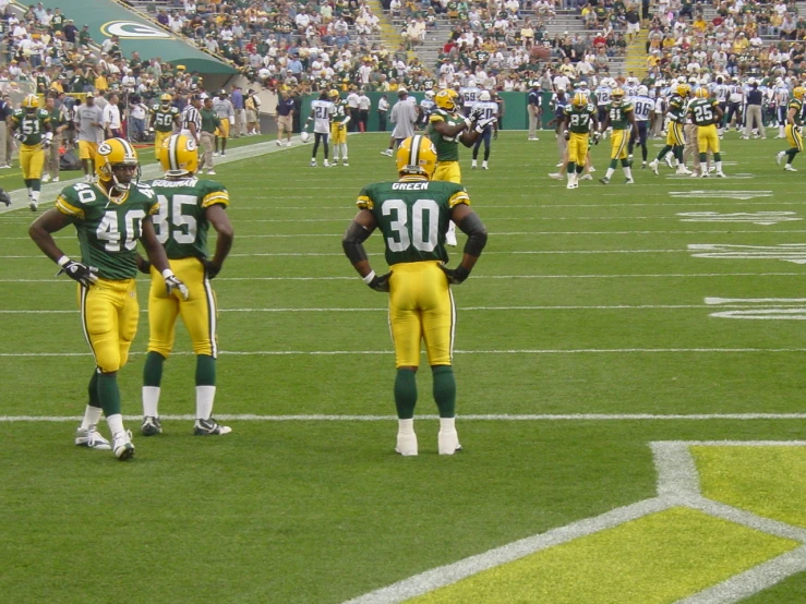 two nfl players standing together on the sidelines of a football game