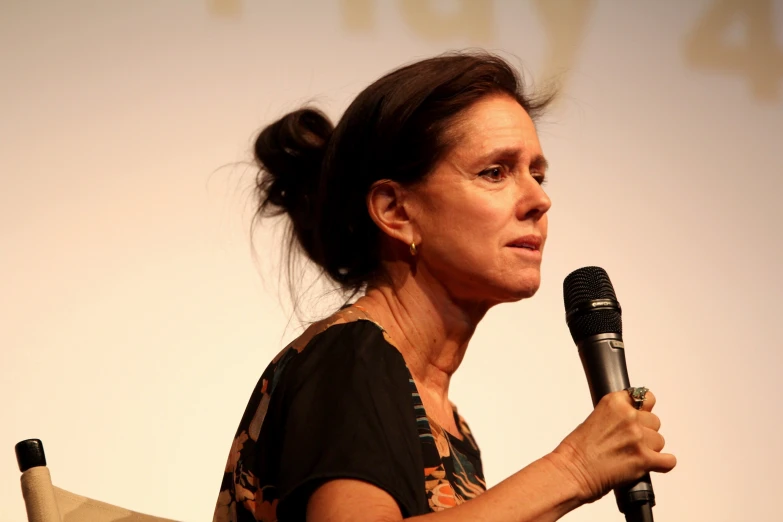 a woman talking into a microphone while holding a mic