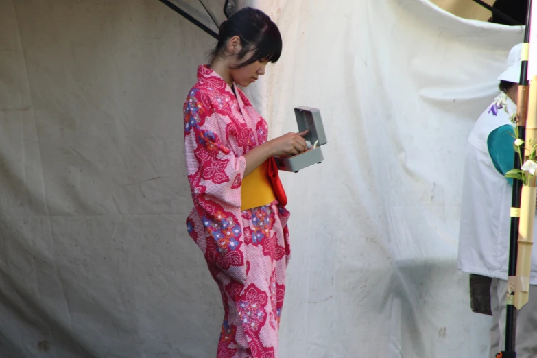 woman in red and pink oriental clothes operating a coin machine