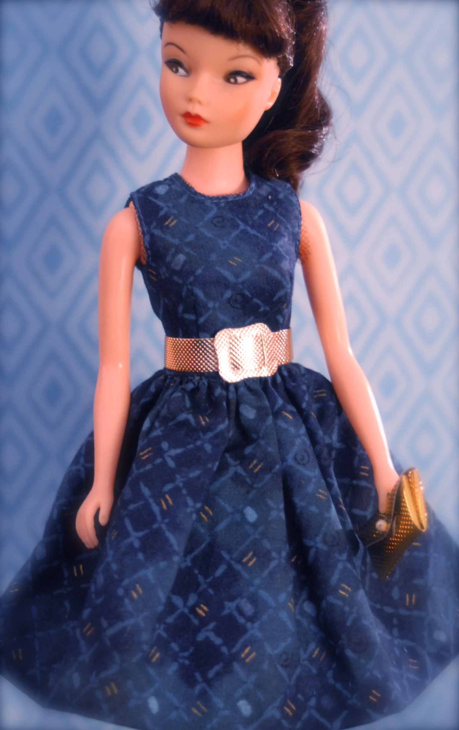a dolls blue dress with gold belt and a purse