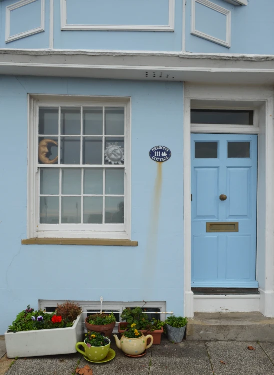 front view of a blue house with flowers by the doors