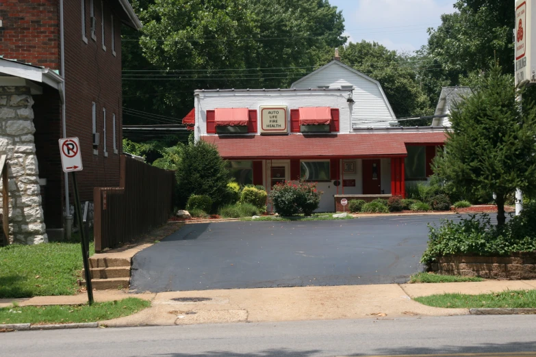 a stop sign and a red house with trees around