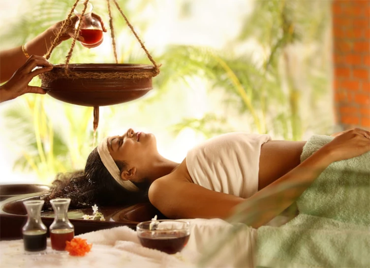 a woman is laying down and having her hair done while having an oil in the spa