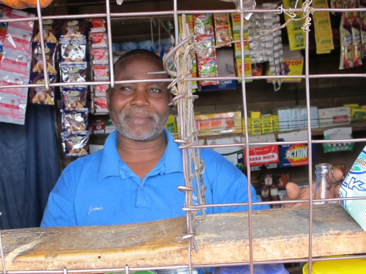 man behind bar cage at outdoor fair selling goods