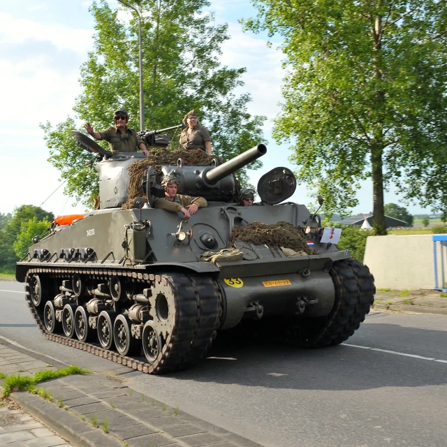 a military tank with two men driving it down the street