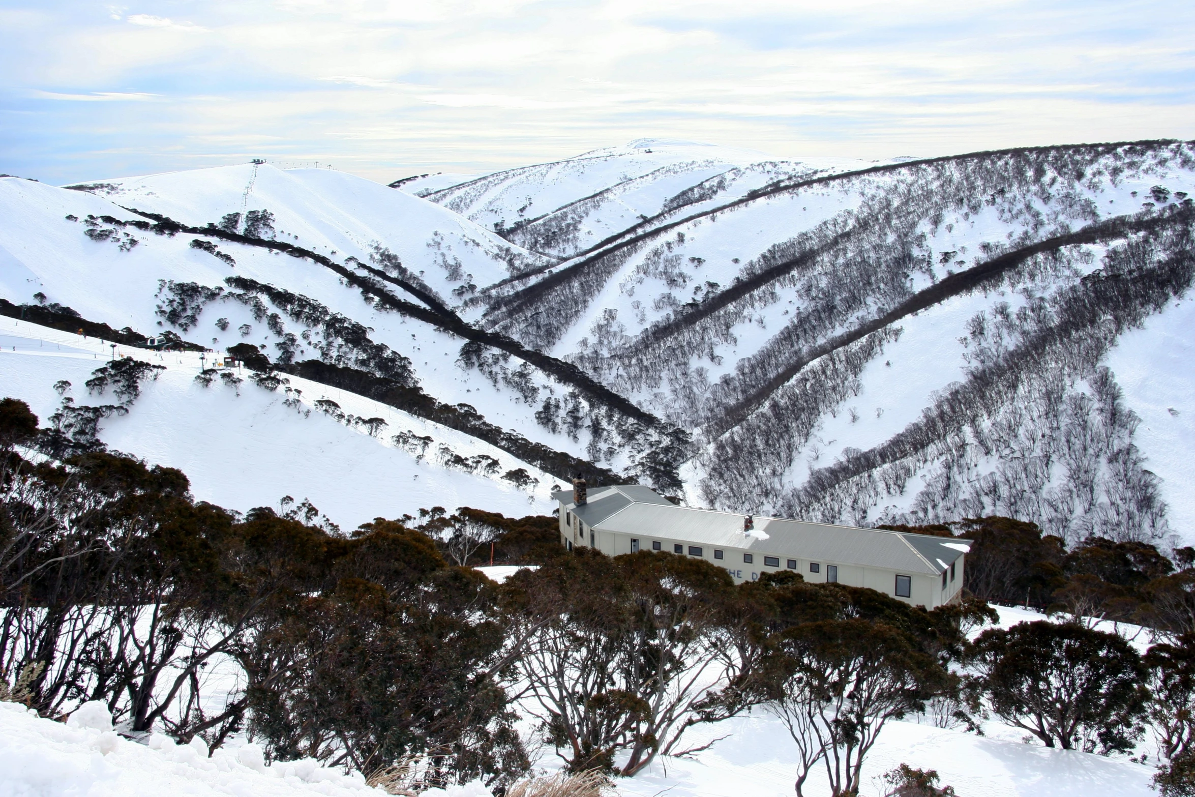 the snowy mountains surrounding the building with many trees