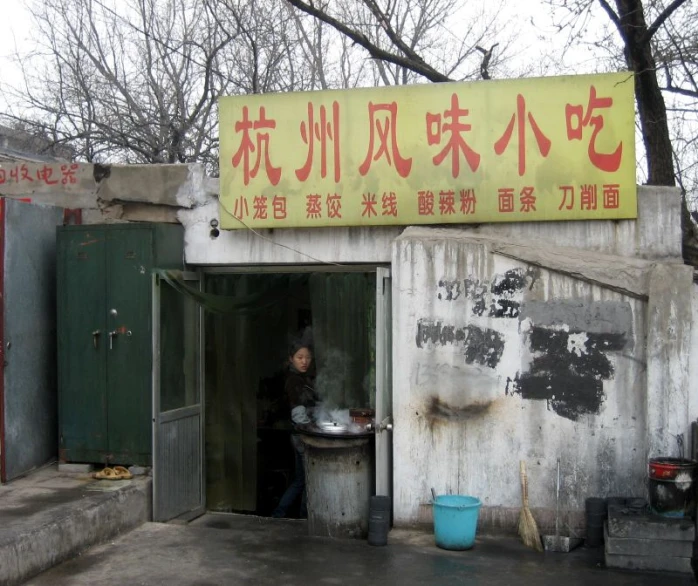 there is a man cooking food outside in this alley