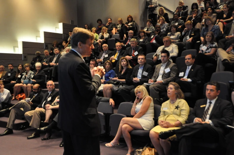 a man standing in front of a crowd while talking to people