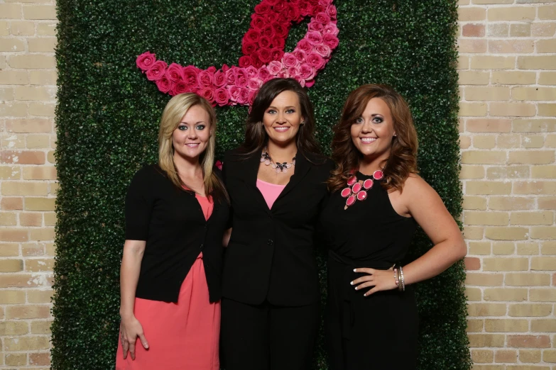 three woman are posing for the camera in front of a green backdrop