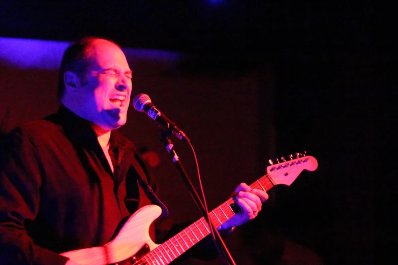 a man singing into a microphone while holding a guitar