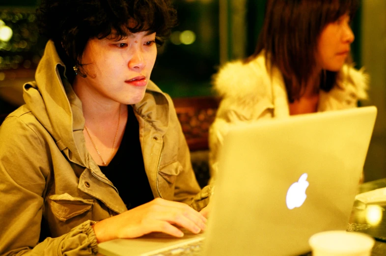 two women using laptops at a bar