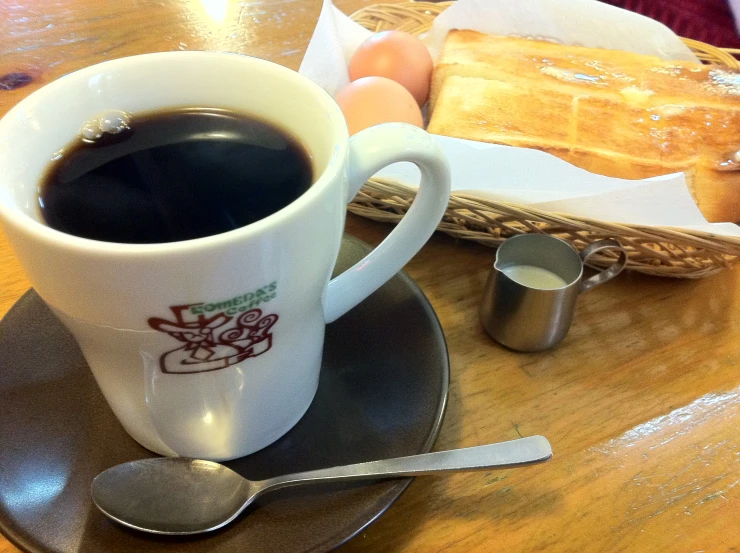the coffee cup sits next to two eggs and a basket on a table