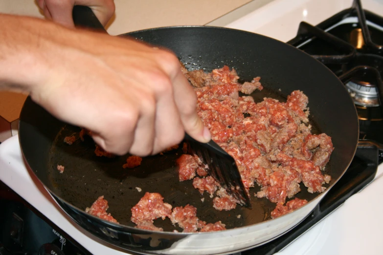 there is a man holding a spatula over some meat