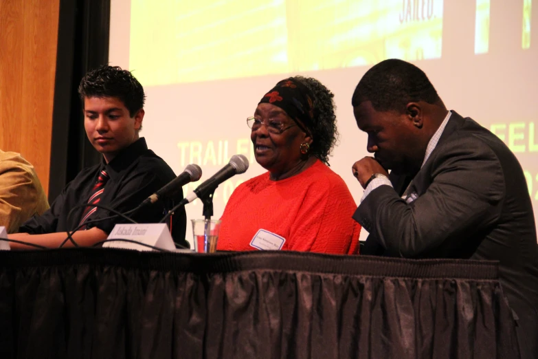 several people sit at a podium with microphones