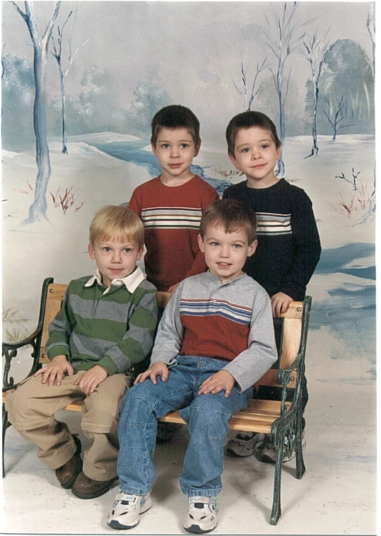 there are four boys sitting on a bench