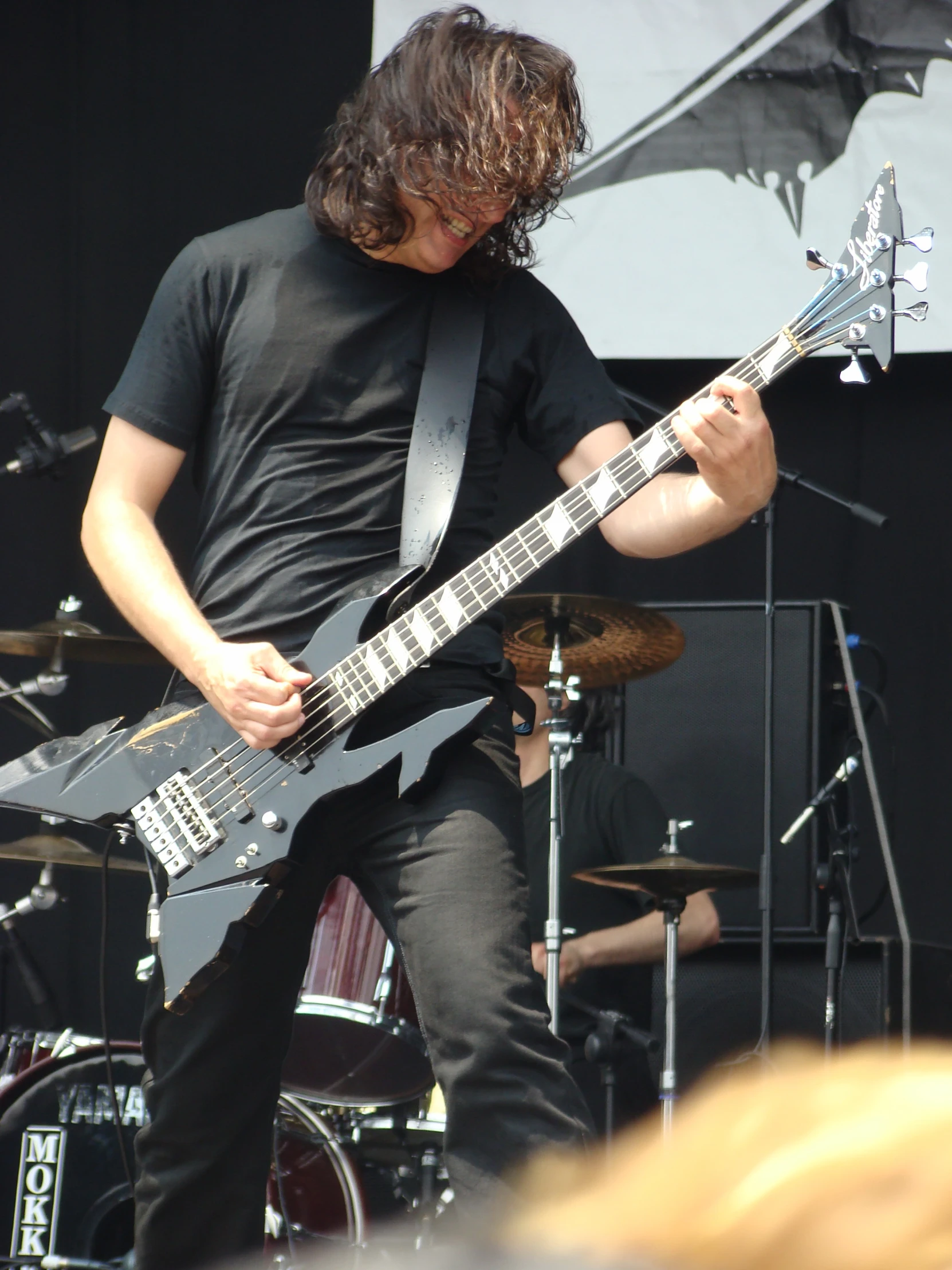 a person with long hair and a black shirt plays a guitar