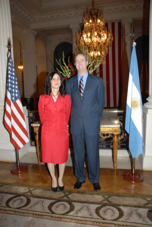 a couple poses in an ornate room before flags