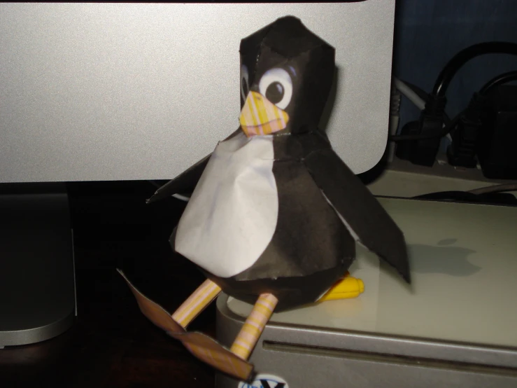 a penguin sitting on top of an open computer monitor