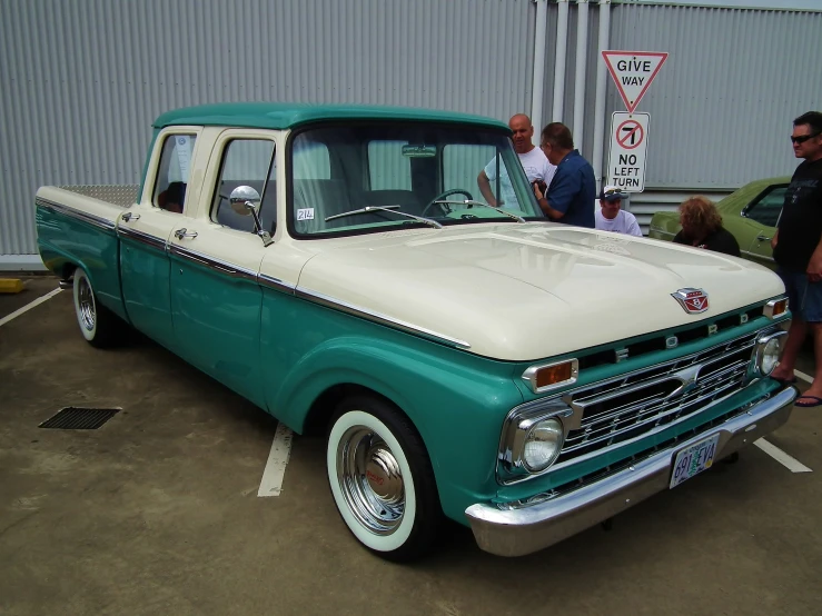 an old green and white truck parked in a parking lot