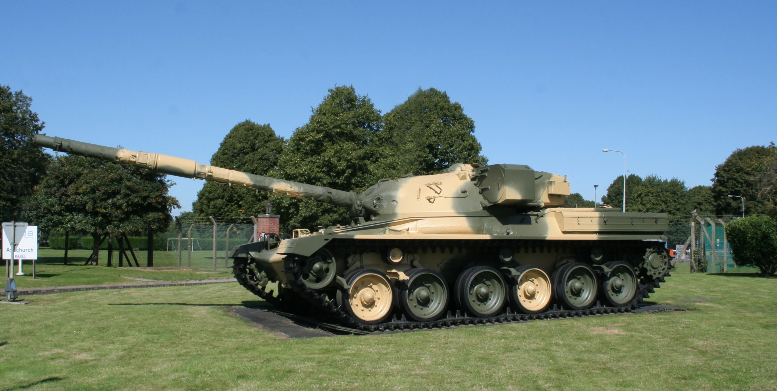 a army vehicle is parked on grass next to trees