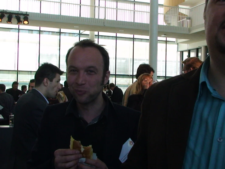 two people eating and a man looking on