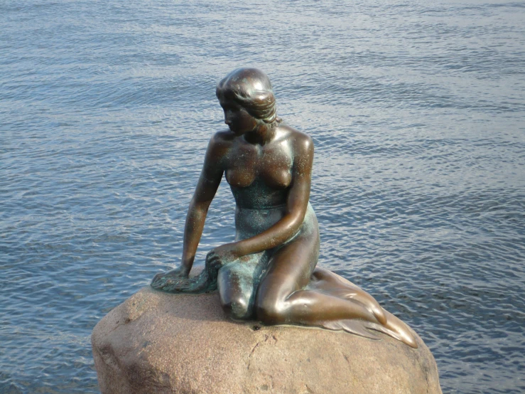 the statue has been placed on a rock overlooking the water