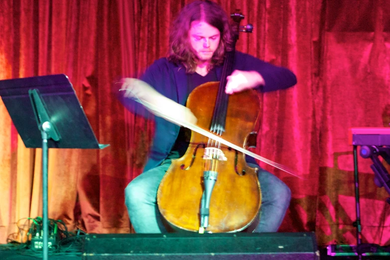 man plays on cello in front of a band