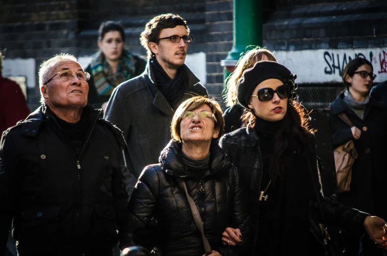 three people are standing on the street near other people