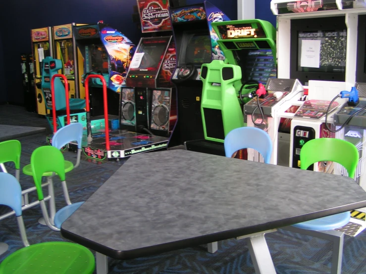 a room filled with table top games and green chairs