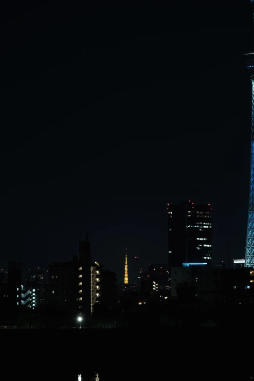 a tall, illuminated clock tower stands above a city at night