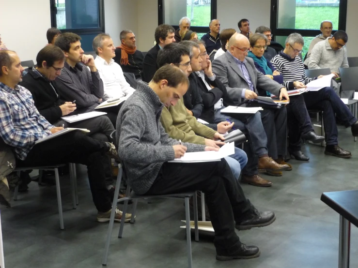 men sit in chairs and listen to their instructor