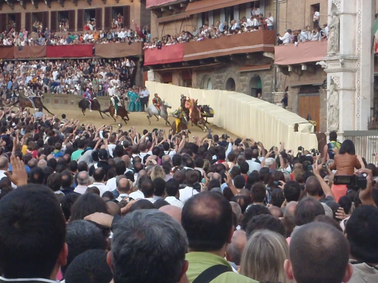 a crowd of people and horses in front of an arena