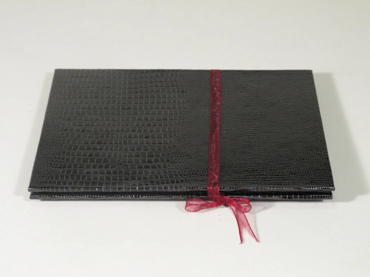 the black leather book is tied with a red ribbon