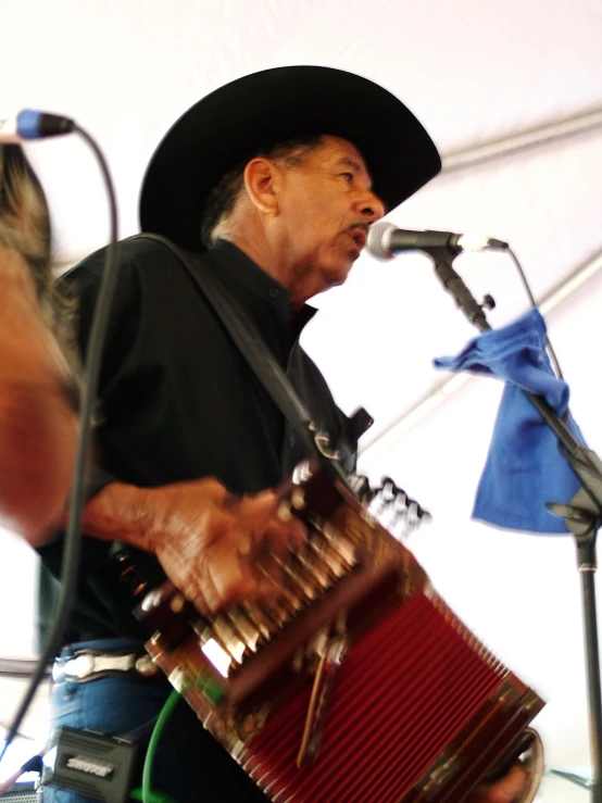 a man holding an accordion and singing into a microphone