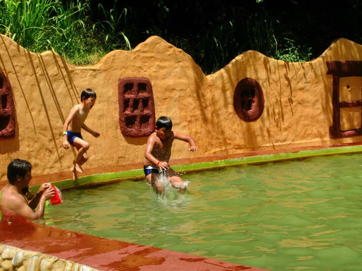 people jump into a pool while wearing swim trunks