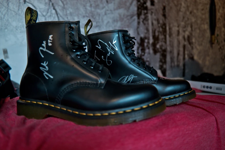 a pair of black leather combat boots with writing on them
