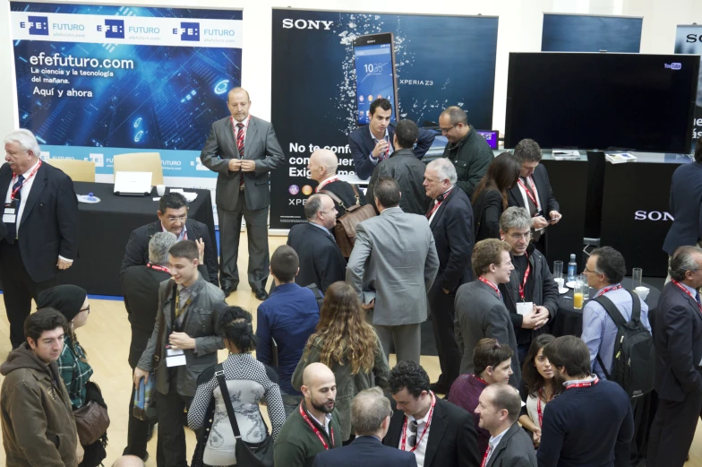 many people standing in front of monitors at a conference