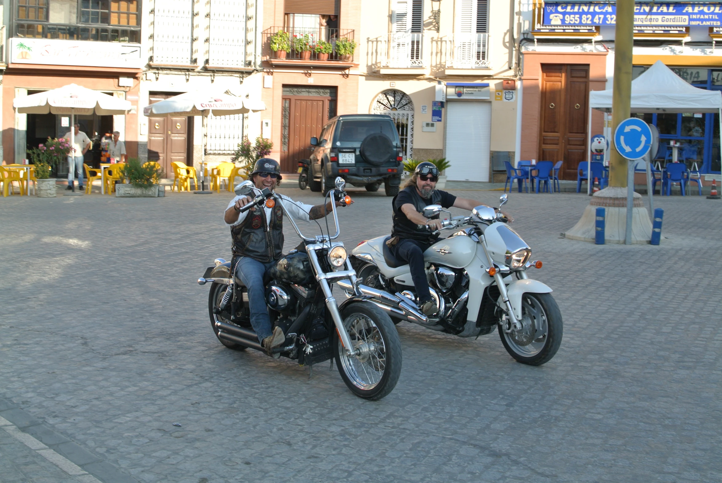the two men are wearing leather jackets and helmets on their motorcycles